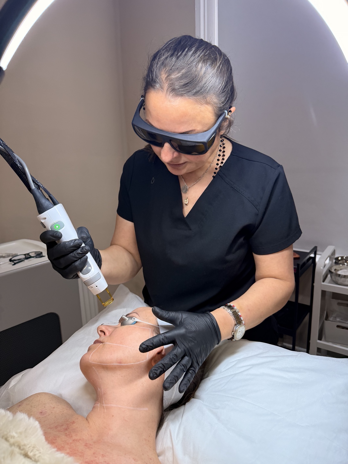 Practitioner performing clinical skin treatment with laser handpiece
